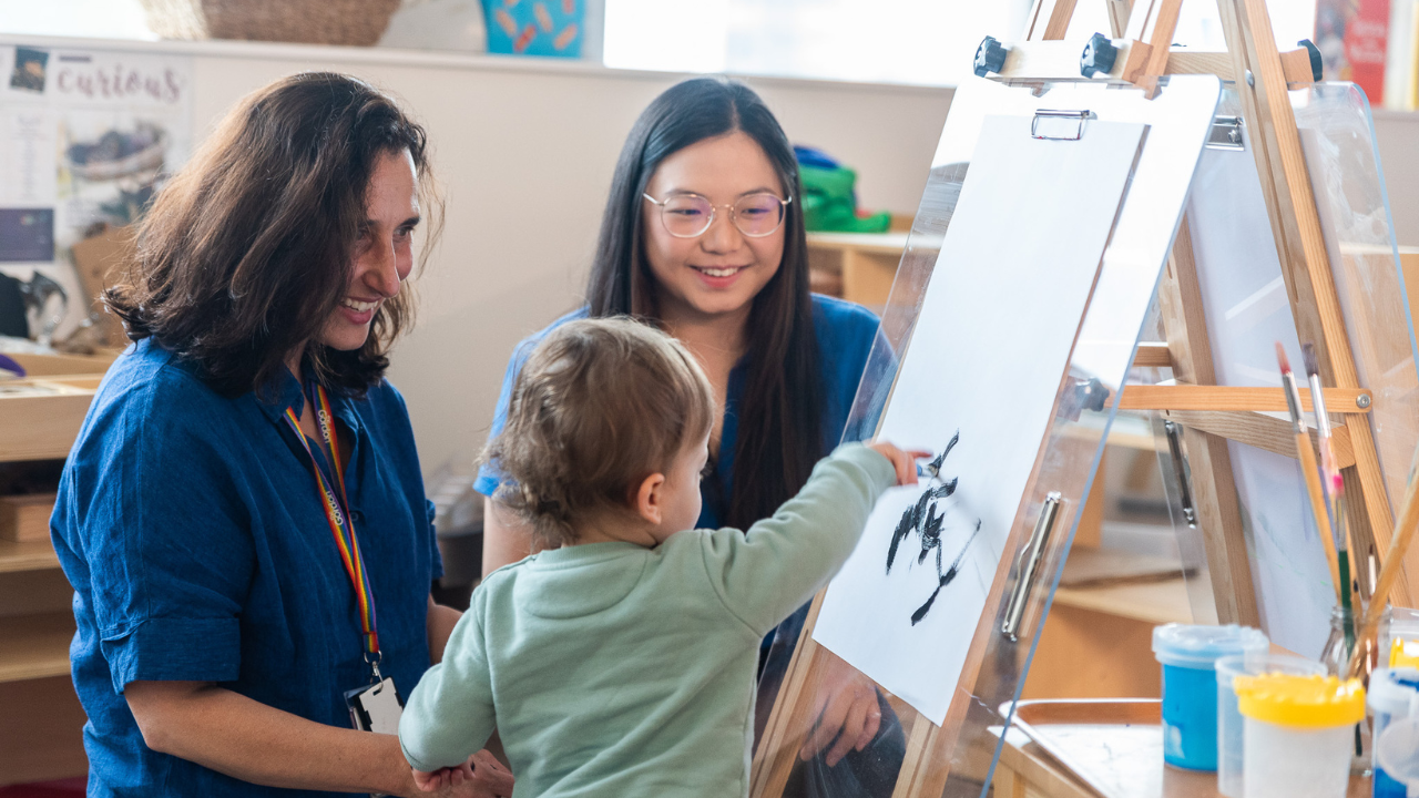 Two women with a young child painting