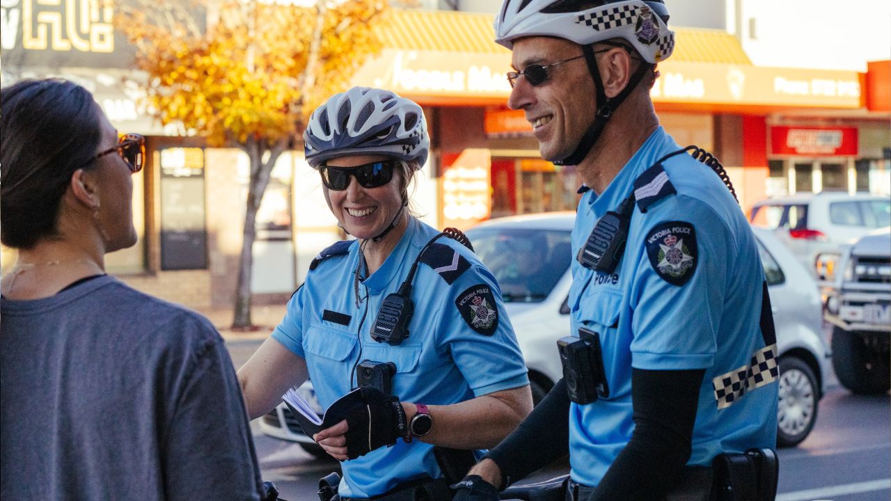 Female and male police officers talking to a woman on a street Female and male police officers talking to a woman on a street