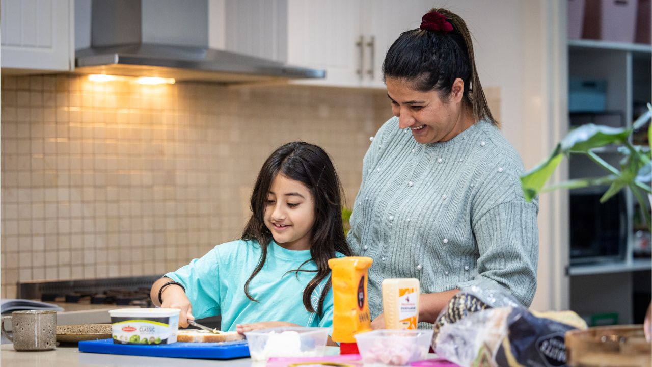 Mother and daughter preparing food in family home kitchen Mother and daughter preparing food in family home kitchen