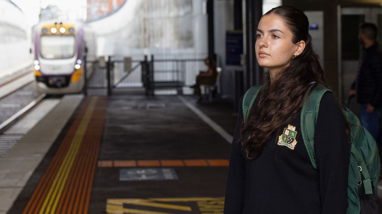 School student standing at a train platform